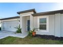 Home featuring an attached garage, a blue door and manicured garden beds at 2408 Bonanza Ln, North Port, FL 34286