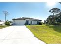Inviting single-story home featuring a concrete driveway and lush green lawn at 2408 Bonanza Ln, North Port, FL 34286