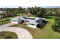 Stylish single-story home featuring a well-manicured lawn, circular driveway, and energy-efficient solar panels on the roof at 310 Green Dolphin Dr, Placida, FL 33946