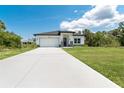 Lovely home with an inviting lawn, long driveway, and attached two car garage, under a bright blue sky at 398 Sunset N Rd, Rotonda West, FL 33947