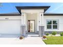 Inviting home entrance featuring a red front door framed by stone pillars and manicured landscaping at 482 Sunset N Rd, Rotonda West, FL 33947