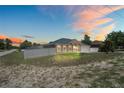 Back exterior view of the home at sunset with an illuminated fenced yard at 5510 Moongate Rd, Spring Hill, FL 34606