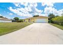 Home exterior showing a spacious driveway leading to an attached two car garage and a well-manicured lawn at 6158 Cavan St, Englewood, FL 34224