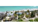 Aerial view showcasing the neighborhood, including a beach house with landscaping and a glimpse of the ocean at 7420 Manasota Key Rd, Englewood, FL 34223