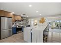 Bright kitchen boasts stainless steel appliances, a large island with seating, and stylish decor with outdoor views at 7530 Whitcomb St, Englewood, FL 34223