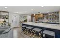 Open kitchen featuring a large island with seating, stainless steel appliances, and stylish backsplash and decor at 7530 Whitcomb St, Englewood, FL 34223