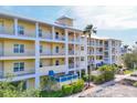 Beautiful condominium exterior featuring multiple stories, white railings, landscaping, and covered parking at 8411 Placida Rd # 404, Placida, FL 33946