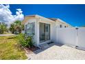 The home's exterior features a quaint patio area, sliding glass doors, fresh landscaping, and a white fence at 859 E 2Nd St, Englewood, FL 34223
