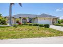 Traditional home with a manicured lawn, arched entryway, white columns, and a spacious driveway leading to an attached garage at 1002 Rotonda Cir, Rotonda West, FL 33947
