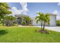 Beautiful gray home featuring tropical landscaping, a paver driveway, and an attached garage at 124 Cutlass Dr, Rotonda West, FL 33947