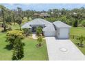 Charming gray home with manicured lawn, tile roof and decorative driveway in a lush, green neighborhood at 124 Cutlass Dr, Rotonda West, FL 33947