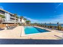 Relaxing outdoor pool with lounge chairs, clear blue skies, palm trees, and beautiful water views at 1591 Beach Rd # 402, Englewood, FL 34223
