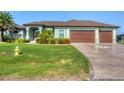 Beautiful single Gathering home featuring a lush lawn, colorful landscaping, and a three-car garage at 204 W Pine Valley Ln, Rotonda West, FL 33947