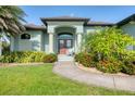 Inviting front entrance to the house, showcasing a well manicured green lawn and colorful landscaping at 204 W Pine Valley Ln, Rotonda West, FL 33947