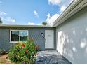 Close-up of the front entrance, showcasing a blue brick facade, stone walkway, and lush flower bushes at 21519 Fairway Ave, Port Charlotte, FL 33952