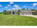 Beautiful home showcasing a lush green lawn, swaying palm trees, and manicured landscaping at 423 Boundary Blvd, Rotonda West, FL 33947