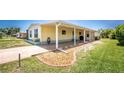 Side view of a yellow mobile home, featuring an attached covered area with decorative stone landscaping at 6293 Sparrow Ln, Englewood, FL 34224