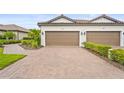 Villa exterior with a two-car garage, brick driveway and tile roof, with meticulously maintained landscaping at 10258 Morning Mist Ln, Sarasota, FL 34241