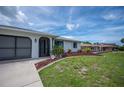 Well-manicured front yard featuring colorful landscaping and a driveway leading to a garage at 15 Oakland Hills Pl, Rotonda West, FL 33947