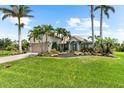 Beautiful home with tropical landscaping featuring mature palms, colorful flowers, and a pristine lawn at 15521 Lakeland Cir, Port Charlotte, FL 33981