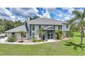 Daytime view of a stately two-story home with lush landscaping, a portico entrance, and mature palm trees at 196 Lecturn St, Port Charlotte, FL 33954