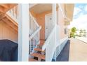 Exterior view of peach-colored home featuring stair access to unit 1C with a grill and parking available at 2373 N Beach Rd # 1C, Englewood, FL 34223
