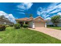 Charming single-story home with a well-manicured lawn, brick driveway, and two car garage at 3207 Village Ln, Port Charlotte, FL 33953