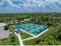 Aerial view of well maintained community pickleball courts surrounded by green space and trees at 3207 Village Ln, Port Charlotte, FL 33953