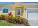 Inviting entryway with a decorative glass front door and colorful landscaping at 576 Box Elder Ct, Englewood, FL 34223