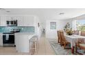 An open-concept kitchen and dining area with white cabinets and a breakfast bar that offers seating for two at 1060 Haste Ln, Englewood, FL 34223