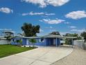 Attractive blue single-story home showcasing an extended driveway and carport with mature landscaping at 1295 S Maryknoll Rd, Englewood, FL 34223