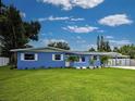 A bright blue single-story home featuring white trim, a green lawn and mature landscaping at 1295 S Maryknoll Rd, Englewood, FL 34223