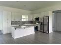 Bright kitchen featuring white cabinetry, stainless steel appliances, an island with quartz countertops, and patterned backsplash at 14149 Whittier Ln, Port Charlotte, FL 33981