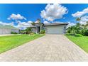 Wide, paved driveway leading to a well-maintained, single-story home with a two-car garage at 15498 Seafoam Cir, Port Charlotte, FL 33981