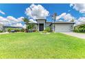 Beautiful single-story home with a manicured lawn, tropical landscaping, and a two-car garage at 15498 Seafoam Cir, Port Charlotte, FL 33981