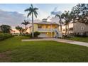 Spacious two-story yellow home boasts lush green lawn and brick driveway leading to the garage at 1784 Bayshore Dr, Englewood, FL 34223