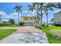 Lovely two-story yellow home with brick driveway, lush lawn, and scenic neighborhood views at 1784 Bayshore Dr, Englewood, FL 34223