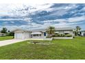 Inviting single-story home showcasing a well-maintained lawn, a charming flowerbed, and an attached single-car garage at 39 Caddy Rd, Rotonda West, FL 33947