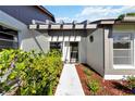 Close-up of the house entrance featuring a covered walkway, decorative plants and bushes, and a glass front door at 609 Deerwood Ave, Englewood, FL 34223