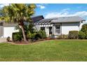 Inviting home with a well-maintained lawn, mature palm, and a covered entryway with stylish architectural detail at 609 Deerwood Ave, Englewood, FL 34223