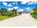 Well-maintained single-story home featuring an attached two-car garage and mature landscaping along the driveway at 7059 Quigley St, Englewood, FL 34224