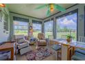 Cozy sunroom with a colorful rug, comfortable chairs, and a dining table set in front of large windows at 7437 Bass St, Englewood, FL 34224