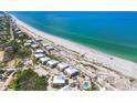 An aerial view showcasing beachfront property with white rooftops and a pool, set against turquoise waters at 7486 Palm Island Dr # 2413, Boca Grande, FL 33921