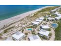 Aerial view of coastal homes with pools and tennis courts, close to the sandy beach and ocean at 7486 Palm Island Dr # 2413, Boca Grande, FL 33921