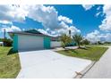 Side view of a charming turquoise home featuring a bright white garage and concrete driveway at 9457 Heartwellville Ave, Englewood, FL 34224