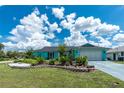 Front exterior of a turquoise home with a lush, green, landscaped yard and a brick retaining wall at 9457 Heartwellville Ave, Englewood, FL 34224