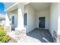 Stylish front porch featuring stone columns, gray shutters, and a modern entry door at 11044 Hogan Cir, Englewood, FL 34223