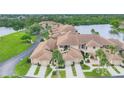A close-up aerial view of a one-story home with an attached garage, manicured lawn, mature trees, and an inviting entrance at 2004 Longpointe Cir # E2, Venice, FL 34293