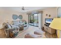 Bright and airy living room features a comfortable plaid sofa and chairs, a ceiling fan, and a sliding glass door at 2004 Longpointe Cir # E2, Venice, FL 34293