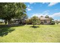 Spacious backyard featuring a screened-in patio, lush lawn, and mature trees offering shade at 27581 Tierra Del Fuego Cir, Punta Gorda, FL 33983